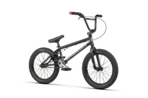 Vista completa de la Wethepeople Curse 18” 2022 negra con tapones de manillar rojos.