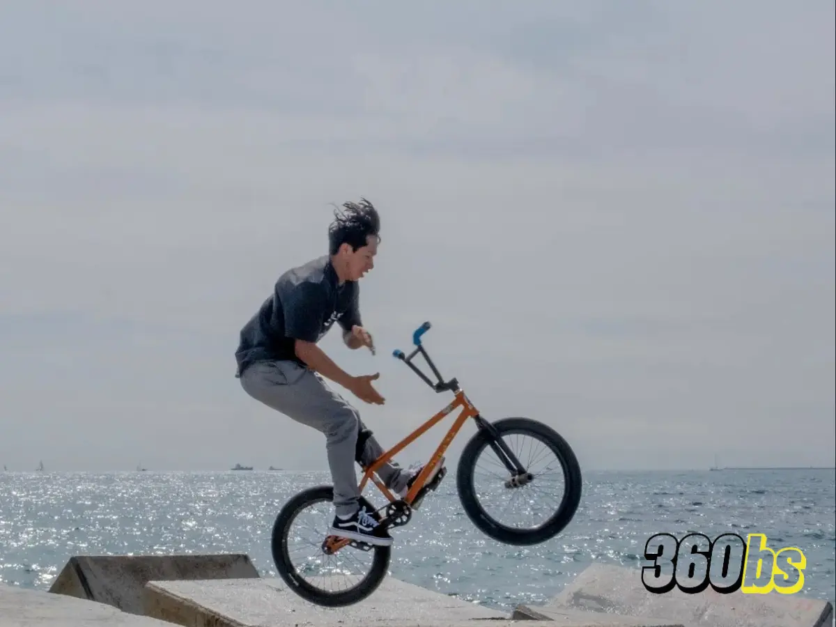 Ciclista ejecutando un truco de BMX con sus rodamientos de bicicleta BMX con el mar de fondo.