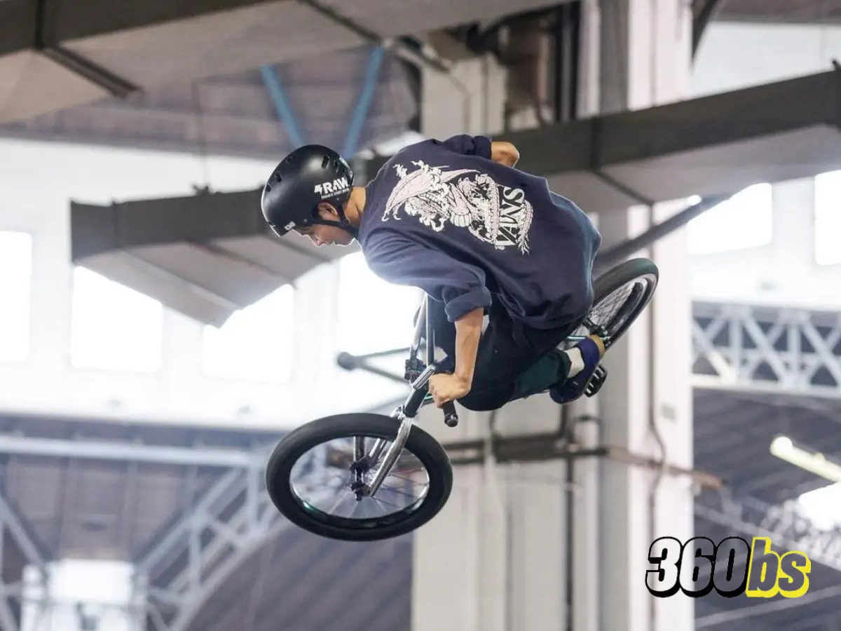BMX en vuelo, mostrando habilidades aéreas en skatepark cubierto.