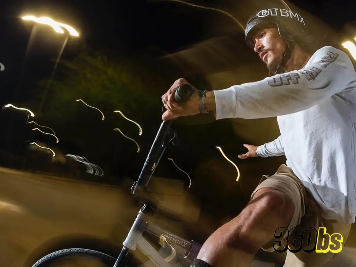 Ciclista de BMX realizando un truco en un skatepark nocturno.