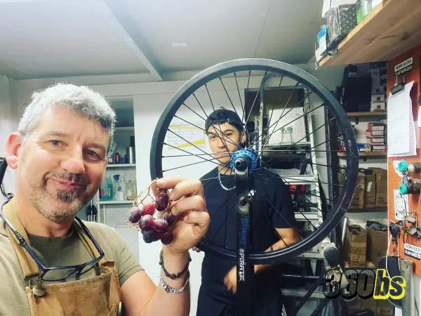 Mecánico de BMX sosteniendo un racimo de uvas en un taller de bicicletas