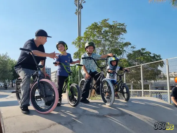 Grupo de niños aprendiendo BMX con instructor en parque