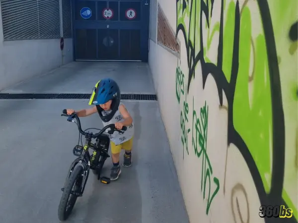 Niño con casco empujando su bici BMX infantil en rampa urbana